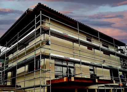 Aplicación del corcho proyectado de textura ELASTICOVER FINE. Casa unifamiliar de dos plantas con andamios y obreros aplicando Elasticover Fine.