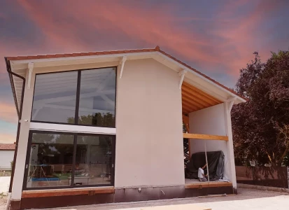 Sistema SATE aislamiento de EPS de 8cm Casa de dos plantas con grandes ventanales, en una de las fachadas, estilo moderno.