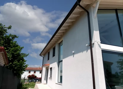 Sistema SATE aislamiento de EPS de 8cm. Casa de dos plantas con grandes ventanales, en una de las fachadas, estilo moderno.