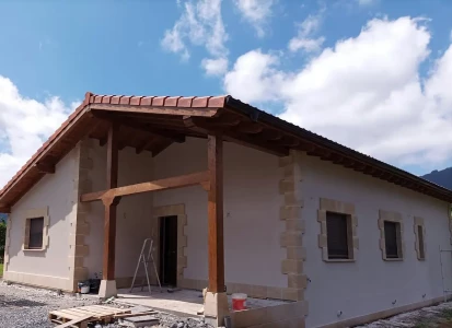 Sistema SATE Aquapanel acabado en corcho proyectado. Casa unifamiliar, de una planta, con porche de madera.