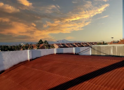 Después de la aplicación de corcho proyectado Elasticover Tech. Después de la aplicación de corcho proyectado rojo, Elasticover Tech, a una cubierta curva de una nave. con otras naves y chalets alrededor.