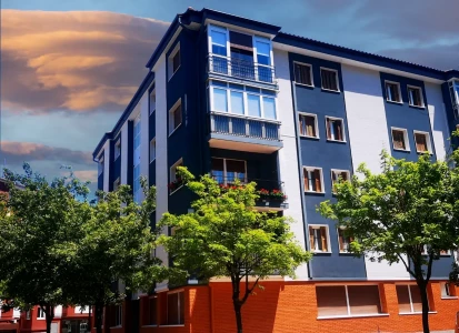 Aplicación de corcho proyectado ELASTICOVER TECH, en un edificio de viviendas. Vista general de un edificio, con cuatro plantas de viviendas, con corcho proyectado ELASTICOVER TECH, en franjas verticales blancas y azules oscuras y árboles a su alrededor