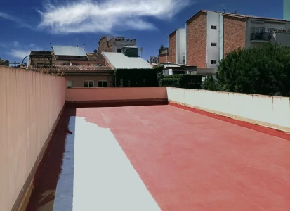Impermeabilización de terraza con fibra MAT Y ELASTICOVER IMPER. Aplicación de impermeabilización Elasticover Imper en una gran terraza en el tejado, rodeada de edificios.