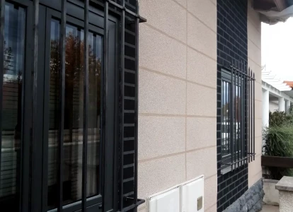 Aplicación de ELASTICOVER FINE y ELASTICOVER TECH imitación a ladrillo. Vista en detalle de las ventanas con rejas de una casa unifamiliar a la que se ha aplicado ELASTICOVER FINE y ELASTICOVER TECH imitando ladrillos y bloques.