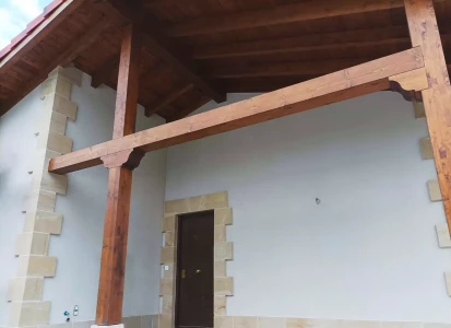 Sistema SATE Aquapanel acabado en corcho proyectado. Casa unifamiliar, de una planta, con porche de madera.